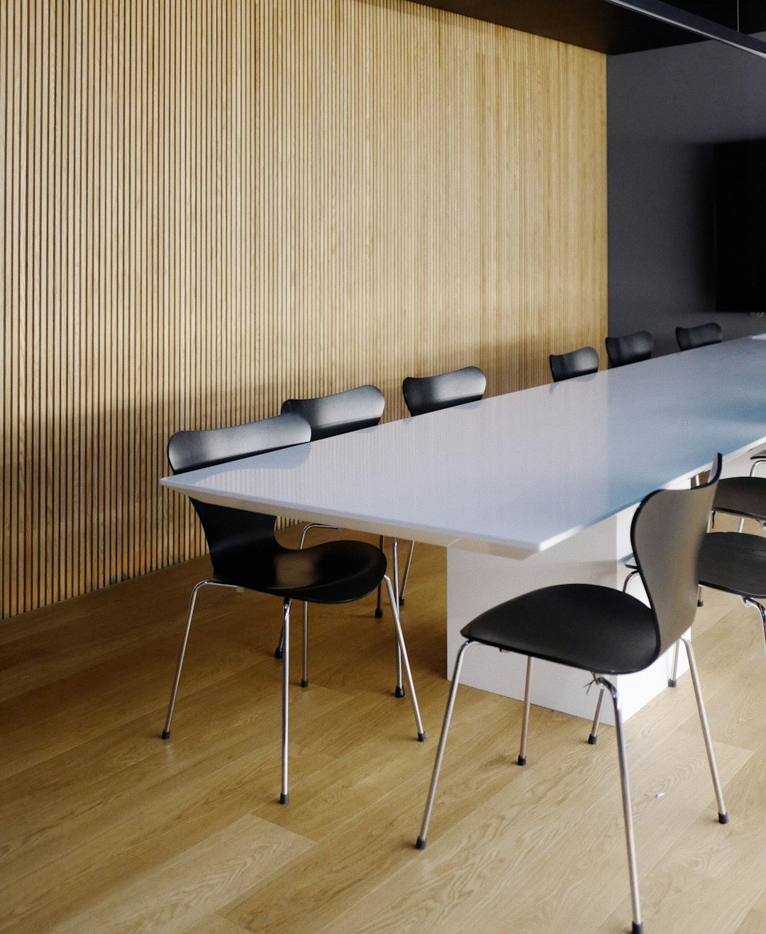 Sala riunioni contemporanea con tavolo chiaro e sedute scure